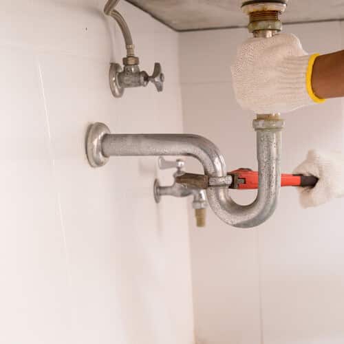 Plumber fixing white sink pipe